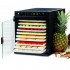 Deshidratador Sedona Express con puerta de cristal abierta, lleno de frutas en rodajas, al lado de una piña.
