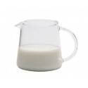 Jarra Trendglas Jena medio llena de leche sobre un fondo blanco.