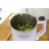 Licuadora abierta MioMat con vegetales picados, ideal para leches vegetales saludables, sobre encimera.