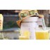 Exprimidor con sombrero de paja y gafas de sol, rodeado de vasos de leches vegetales saludables.