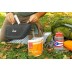 Persona vertiendo agua en una bolsa de comida Pad Thai al aire libre, rodeada de equipos de cocina solar.