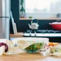 Cuencos con tapas con estampado de abejas en la encimera de la cocina; verduras de Bee's Wrap en el interior.