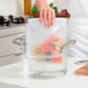Persona colocando una bolsa de silicona reutilizable con salmón en una olla con agua para cocinarlo al vacío.