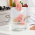 Persona colocando una bolsa de silicona reutilizable con salmón en una olla con agua para cocinarlo al vacío.