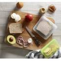 Tabla de madera con ingredientes para hacer sándwich y una bolsa de silicona reutilizable para guardarlos.