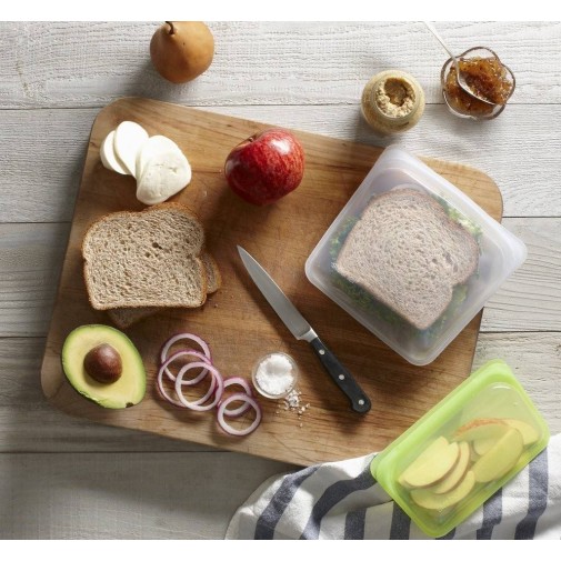 Tabla de madera con ingredientes para hacer sándwich y una bolsa de silicona reutilizable para guardarlos.