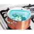 Bolsa hermética de silicona platino con verduras hirviendo en una olla de cobre sobre una estufa.