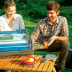 Pareja sonriente cocinando con un horno solar GoSun Fusion en un picnic.
