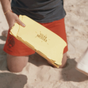 Persona arrodillada sobre la arena con un horno solar "Solar Brother", perfecto para recetas sencillas.