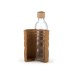 Botella de cristal con tapón de madera en estuche protector marrón.