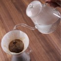 Hervidor de agua vertiendo agua sobre café filtrado.