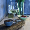 Copa de vino blanco con frutos secos y fresas sobre una tabla de madera.