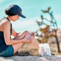 Mujer aplicándose una venda en la rodilla mientras está al aire libre.