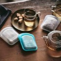 Kit de 2 bolsas de silicona Stasher en una mesa con té y bocadillos.