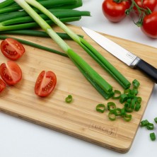 Tabla de cortar de cocina con cebollino y tomate pera cortados