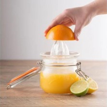 Exprimiendo una naranja en el tarro exprimidor de vidrio Kilner