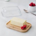 Recipiente de mantequilla con la tapa quitada y una mantequilla perfecta sobre la base de bambú