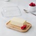 Recipiente de mantequilla con la tapa quitada y una mantequilla perfecta sobre la base de bambú