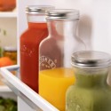 Varias botellas para zumo y salsas Kilner en la puerta de la nevera