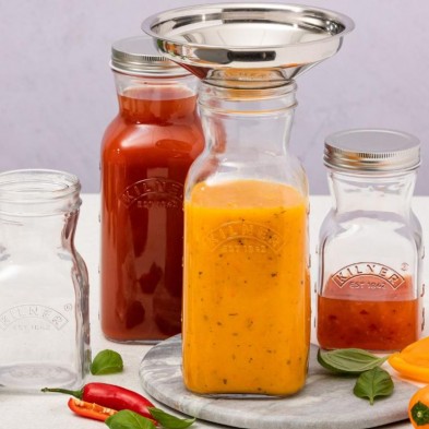 Varias botellas para zumo y salsas Kilner rellenando con el embudo de boca ancha alimentos líquidos