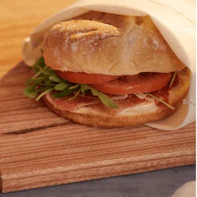 Bolsa de tela para sándwich Food Huggers con un bocata vegetal asomando la bolsa de tela Bolsa de tela para sándwich Food Huggers con un bocata vegetal asomando la bolsa de tela