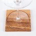 Copa de vino sobre posavasos de madera con motivos geométricos de la flor de la vida