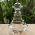 Elegante jarra vitalizadora de vidrio con tapón oro 24 quilates y diseño del árbol de la vida sobre una mesa de madera.