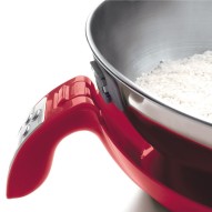 Primer plano de una balanza de cocina electrónica roja con un cuenco de arroz blanco encima.