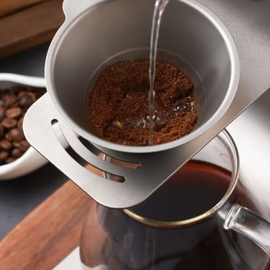 Detalle de la Cafetera de titanio y borosilicato Pour Over kit Keith haciendo café por goteo
