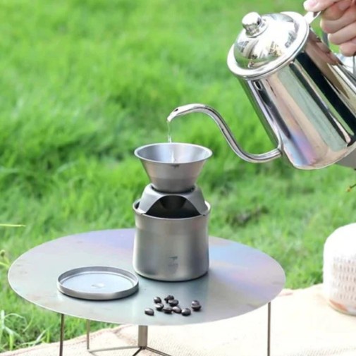 Una persona vierte agua caliente para hacer café al aire libre sobre el mini kit cafetera tetera Keith