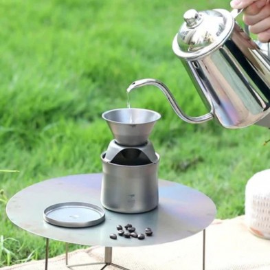 Una persona vierte agua caliente para hacer café al aire libre sobre el mini kit cafetera tetera Keith