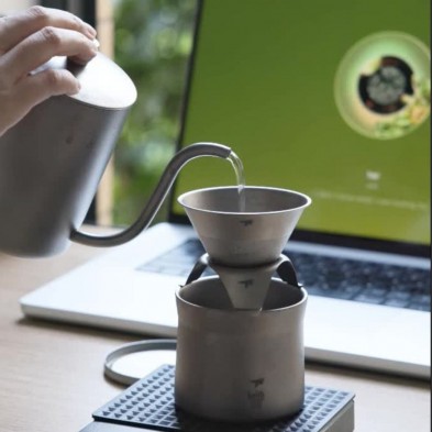 haciendo café con el kit de cafetera Keith, con un ordenador portátil de fondo.