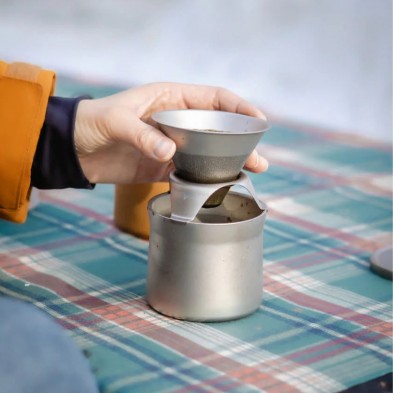 Una mano sirve café sobre la taza del kit de cafetera keith