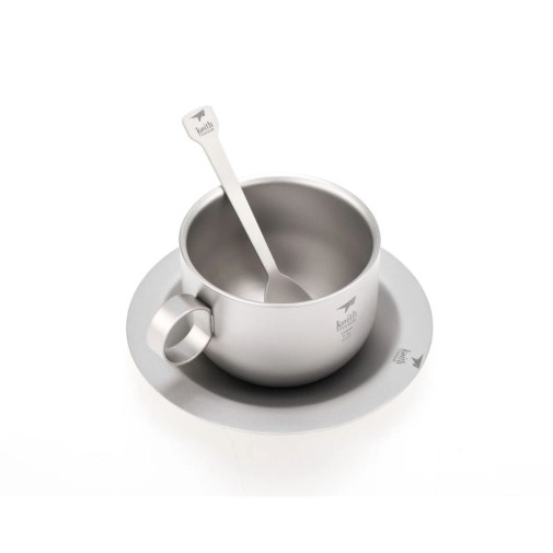 Taza plateada con asa, cuchara en el interior, sobre platillo a juego, todo con diseño minimalista hecho de titanio
