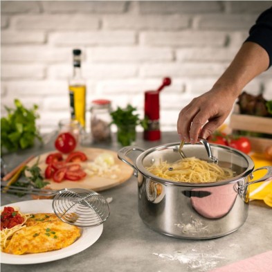 Una mano remueve espaguetis en la olla ALLROUND Kuhn Rikon sobre la encimera de una cocina con ingredientes frescos cerca. Una mano remueve espaguetis en la olla ALLROUND Kuhn Rikon sobre la encimera de una cocina con ingredientes frescos cerca.