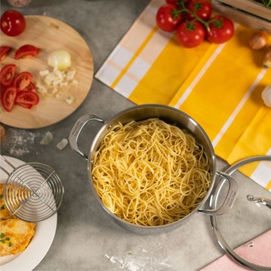 La olla ALLROUND llena de espaguetis cocidos rodeada de ingredientes y utensilios de cocina sobre una encimera. La olla ALLROUND llena de espaguetis cocidos rodeada de ingredientes y utensilios de cocina sobre una encimera.