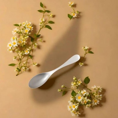 La Cuchara titanio pequeña Keith posada en una superficie con bonitas flores blancas