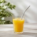 Pajita titanio curvada Keith en un vaso con zumo de naranja