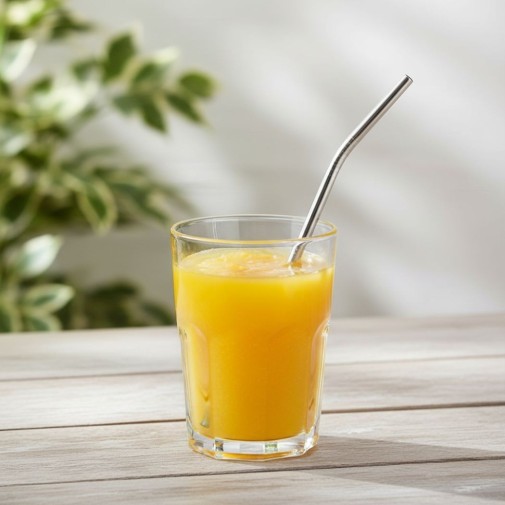 Pajita titanio curvada Keith en un vaso con zumo de naranja