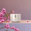Taza titanio japonesa Keith en una mesa con flores de orquídeas de color rosa