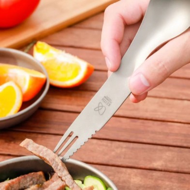 El Cubierto de titanio multiuso keith pinchando con el extremo del tenedor un trozo de carne