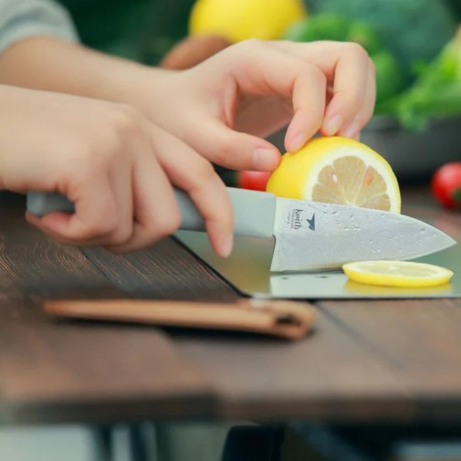 Cuchillo de titanio pequeño Keith con funda de cuero sobre la mesa y cortando con él una rodaja de limón