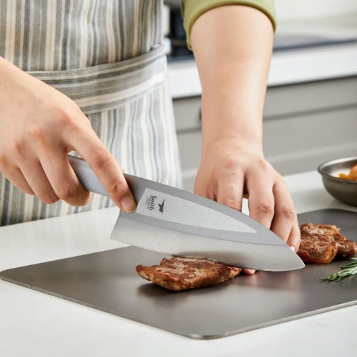 Cortando carne sobre la tabla de titanio con el Cuchillo de titanio grande Keith