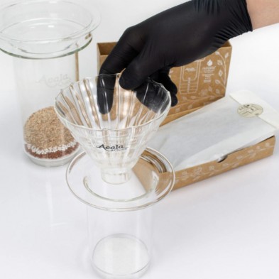 Una mano con guante negra colocando el Embudo de vidrio Riffilo sobre el cartucho rellenable de vidrio de AcalaQuell