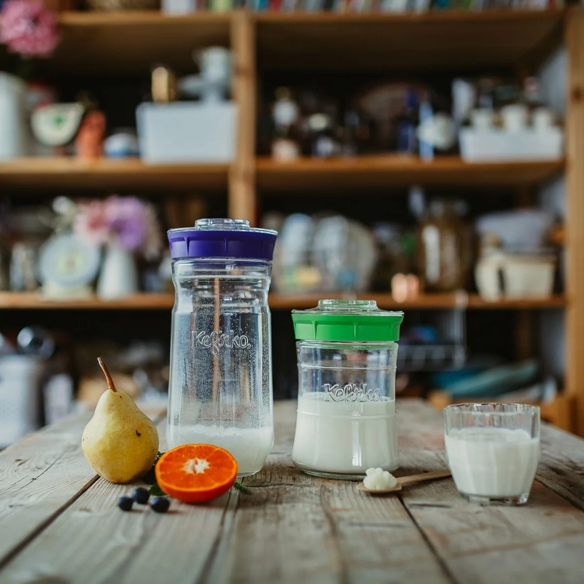 Tarros Kefirko con kéfir de leche y kéfir de agua junto a un vaso servido sobre una mesa de madera