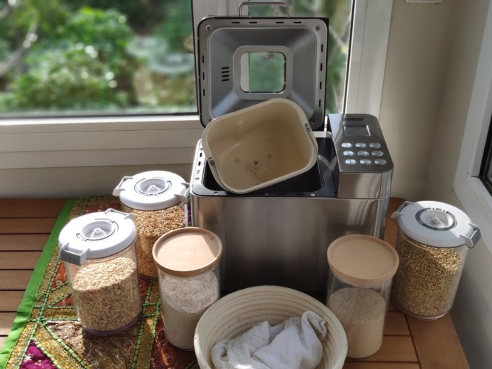 Panificadora Unold acompañada de harinas y granos para hacer pan envasadas en botes de vidrio de borosilicato y tuppers al vacío disponibles en Ecovidasolar